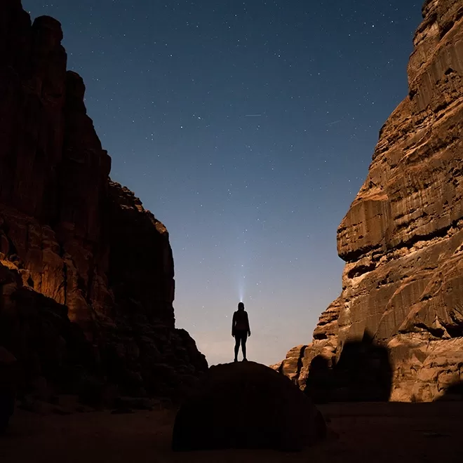 Women stood with headtorch between stoney hills in NEOM
