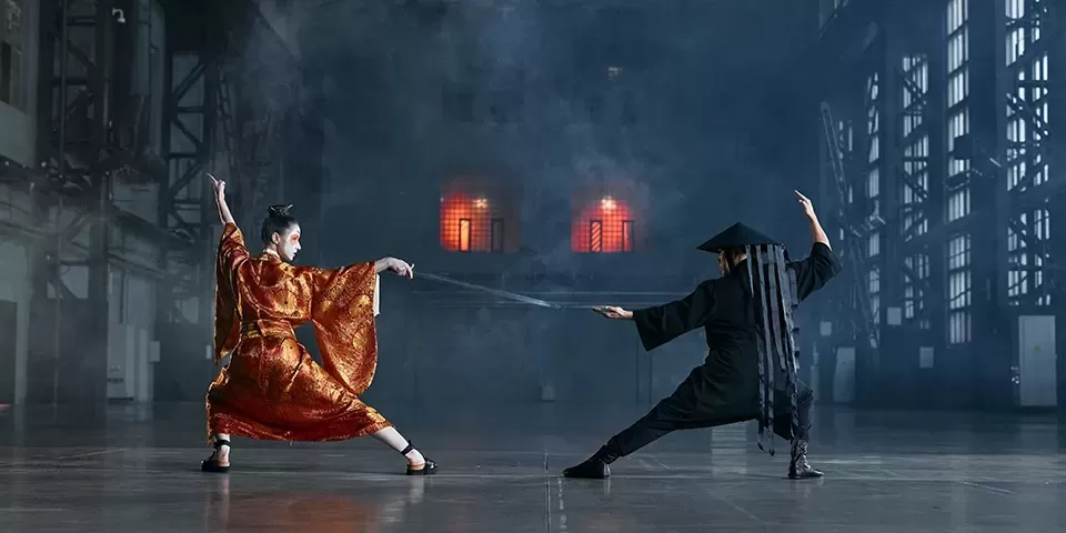 Two Japanese dancers in traditional Japanese dress and make up dancing in an empty hall.