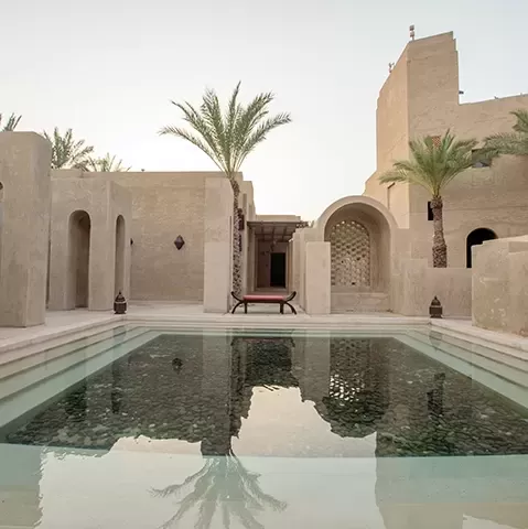 Tranquil pool in centre of stone building and palm tree