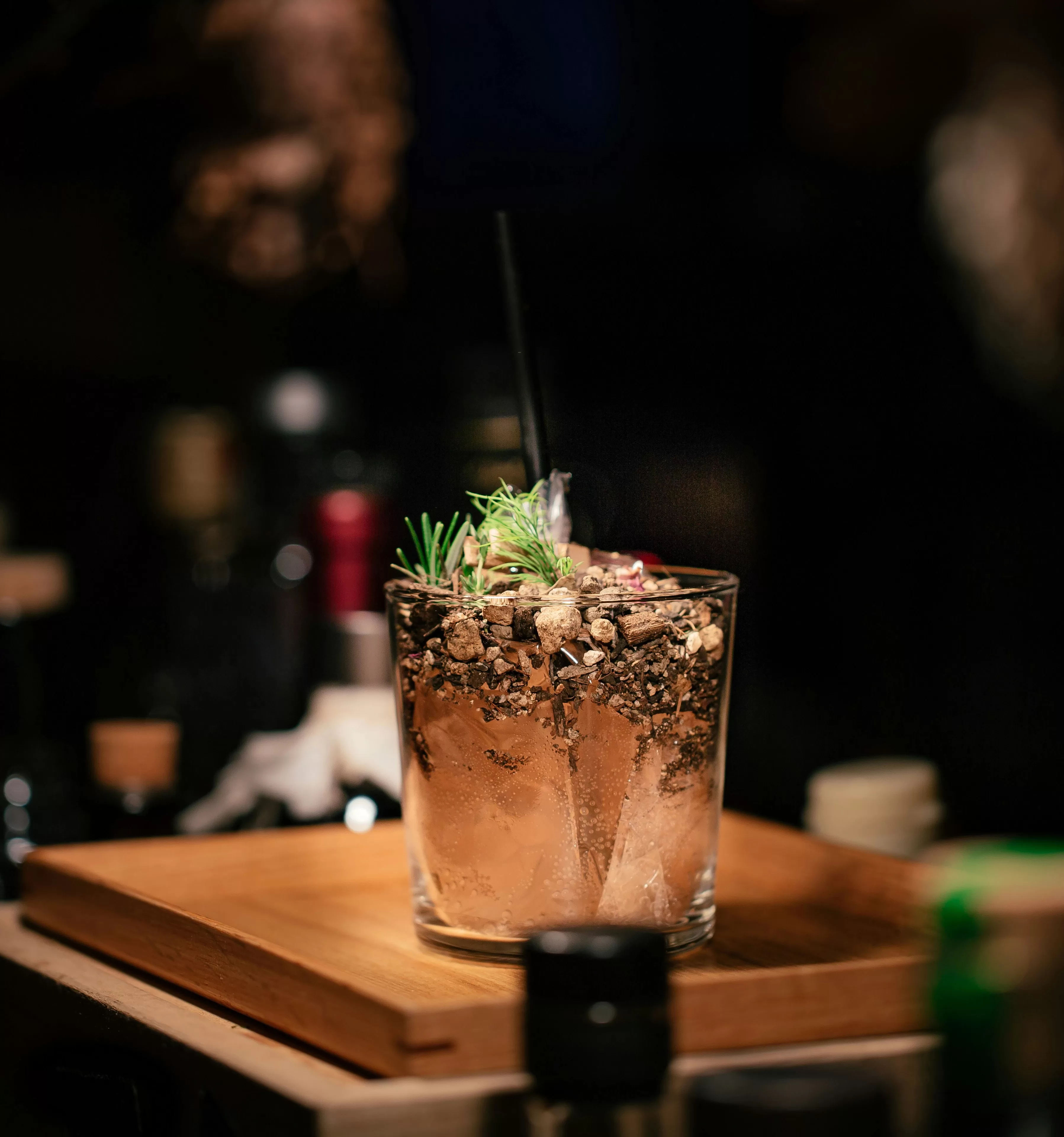 Glass of a cold cocktail with a garnish on a wooden bar top