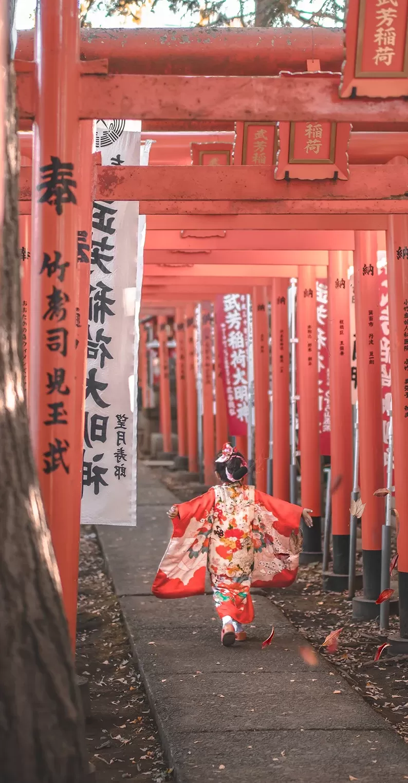 Little girl in traditional Japenese dress running with her hands out along a pathway