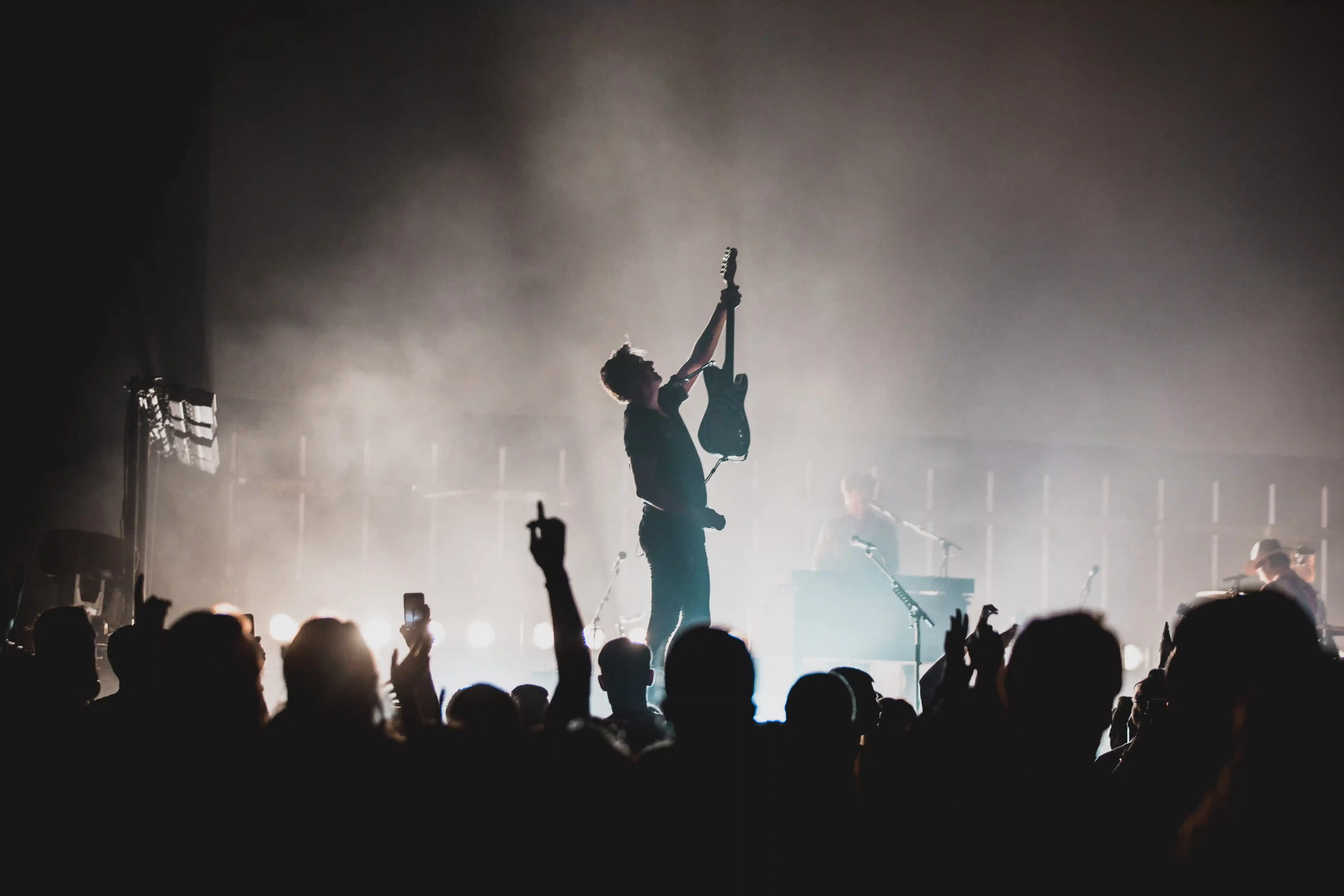 Man on staging holding up guitar to audience
