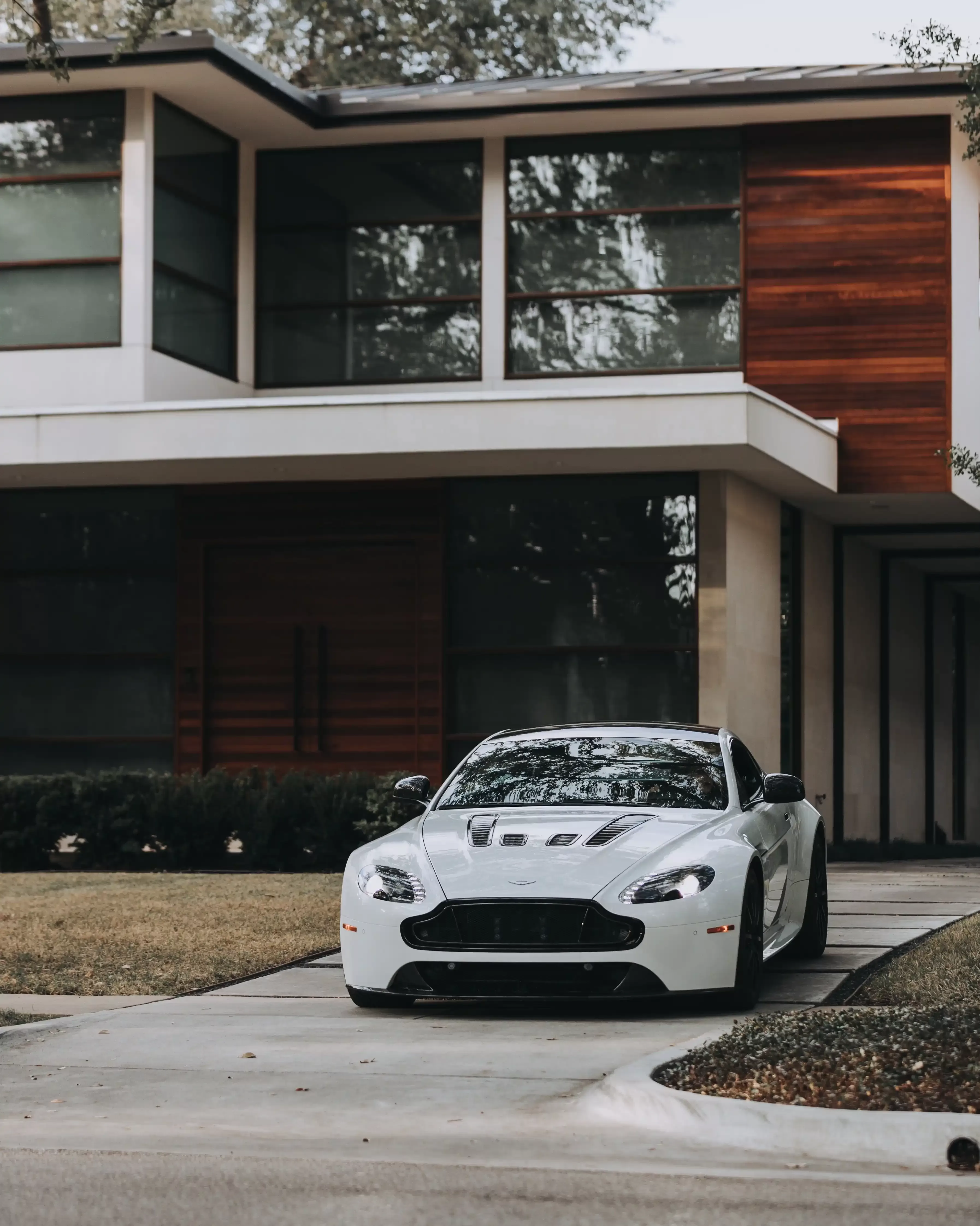 Luxury white sportscar parked in drive of luxury modern home