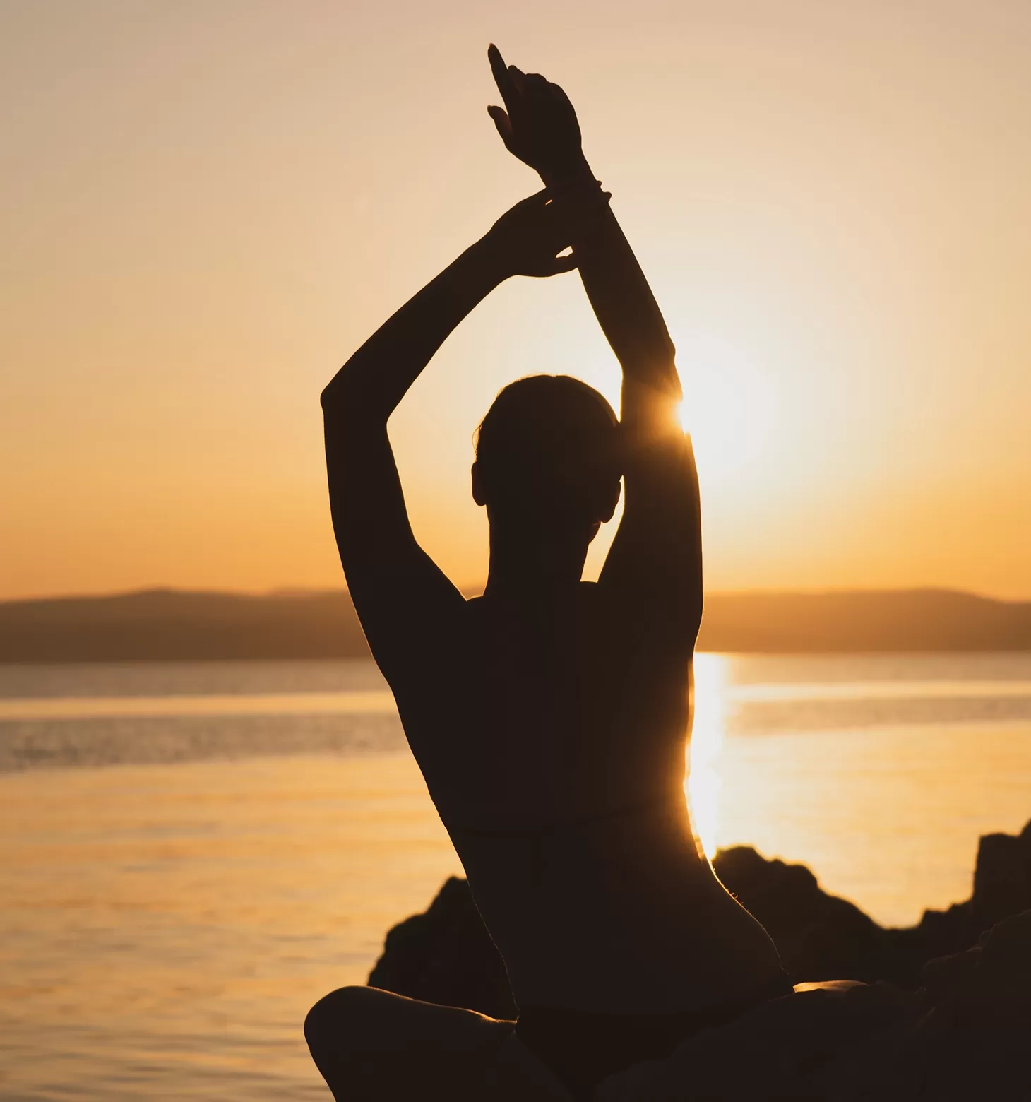 women doing yoga outside on matts with view of the sunset