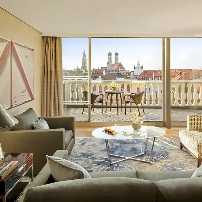 Luxurious suite in the Mandarin Oriental Hotel, Munich, featuring modern decor with a panoramic view of the city’s skyline.