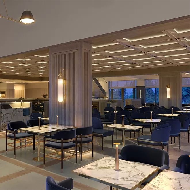 A modern restaurant interior with marble tables, blue cushioned chairs, and warm ambient lighting. The space features clean lines, wooden accents, and large windows showing trees outside.