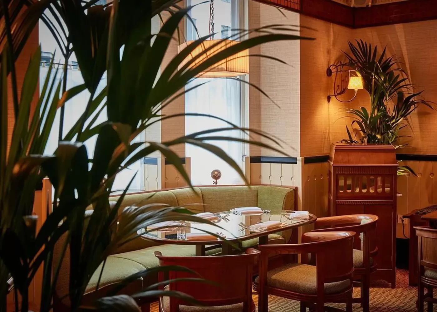 Luxury green round sofa and chairs dining table with large tree at 20 Berkeley, Mayfair, London