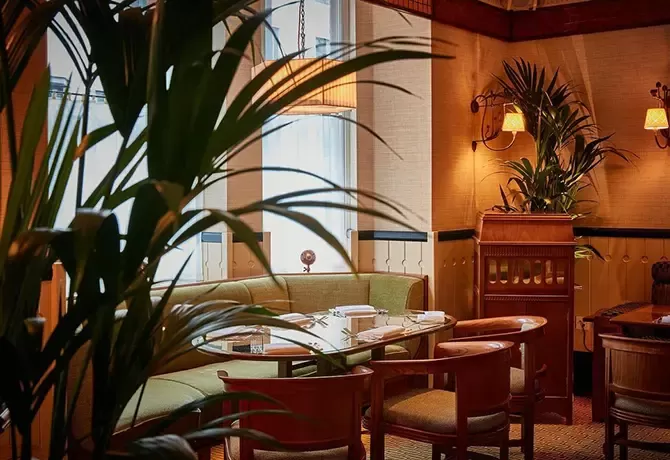 Luxury green round sofa and chairs dining table with large tree at 20 Berkeley, Mayfair, London