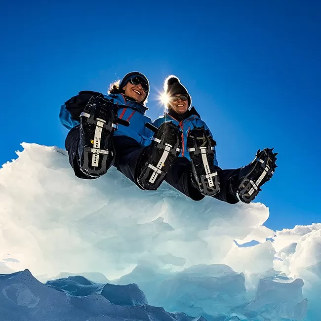 Ben Saunders and Tarka L’Herpiniere posing on an iced ledge
