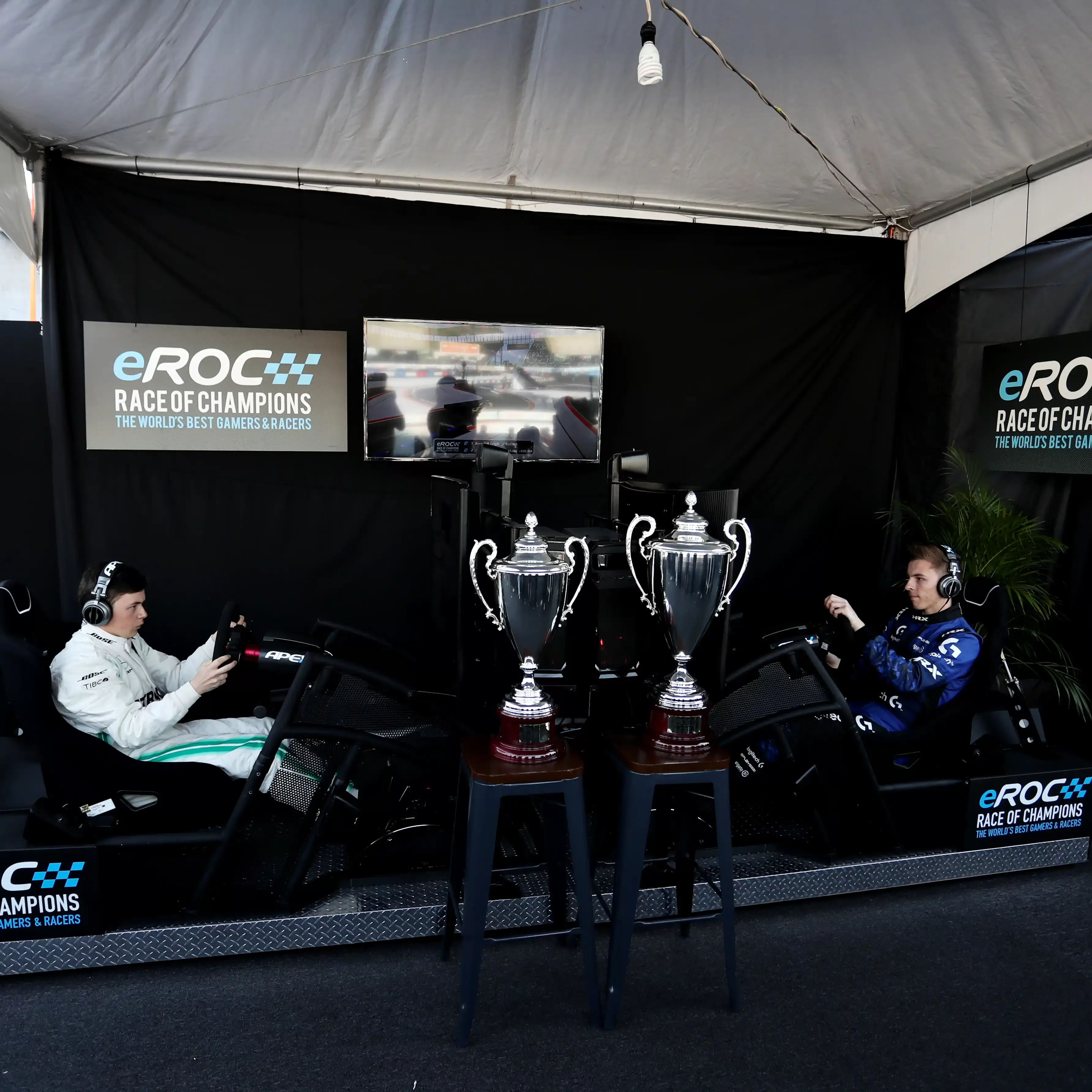 Men playing on race car simulation machine behind the Roc Snow and Ice trophies