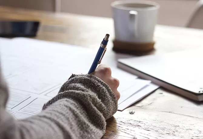 Person writing in a notebook at a desk