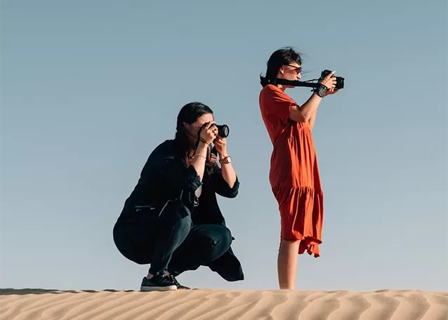 Two females taking photos on professional cameras whilst standing in the dessert stand.