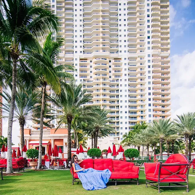 Woman lounging on a red chair with a high rise white building behind her