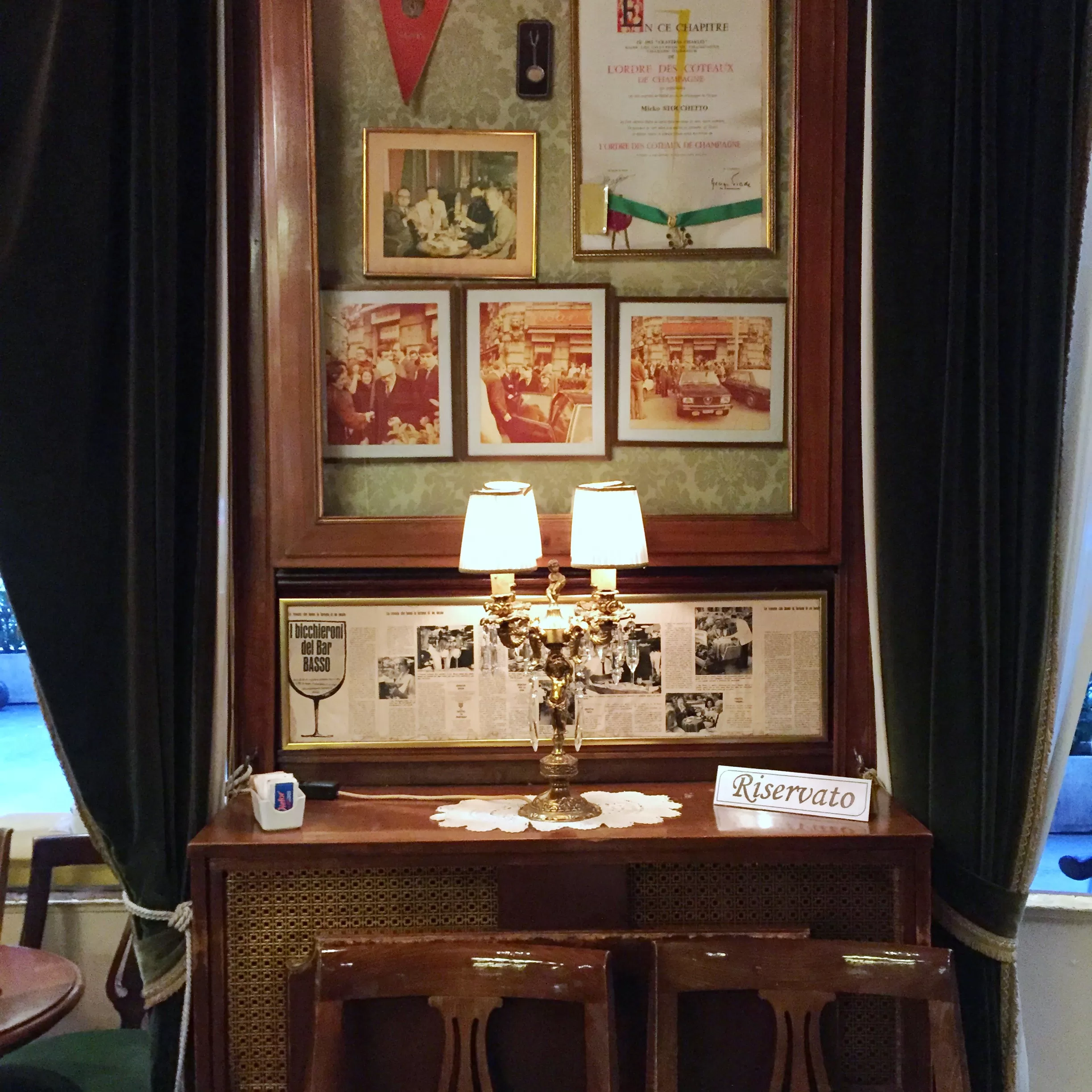Vintage Italian inspired interior with framed vintage memories and reserved small wooden stool table at Bar Basso, Milan