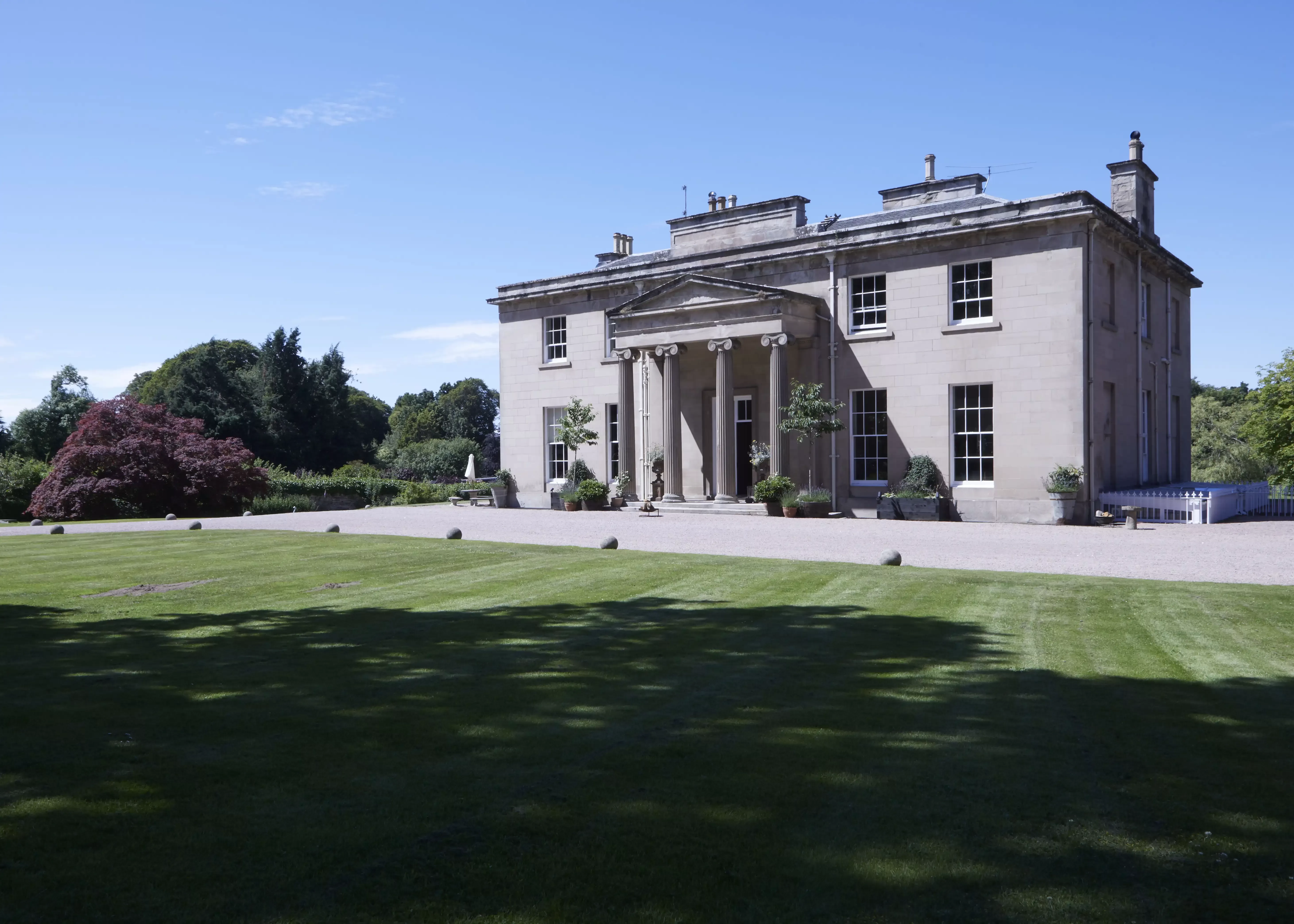 Grand white building exterior with cut grass outside Boath House, Nairn