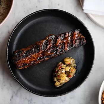 Beautifully smoked dish of food served in a plate at Caia, London