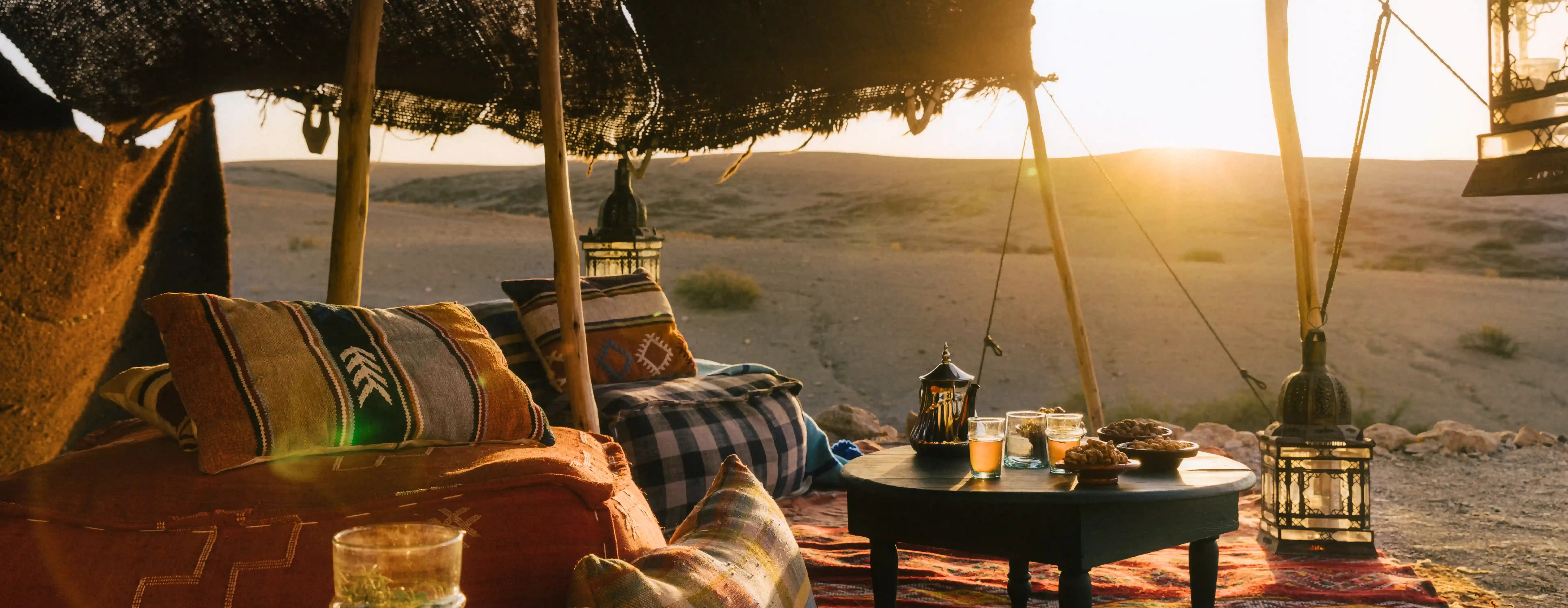 Cosy outside lounge area on blankets with a fabric roof in the desert of Caravan Agafay, Morocco