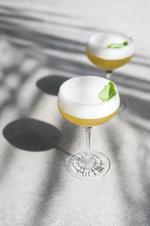 2 cocktails in cocktail glasses with lime garnish.