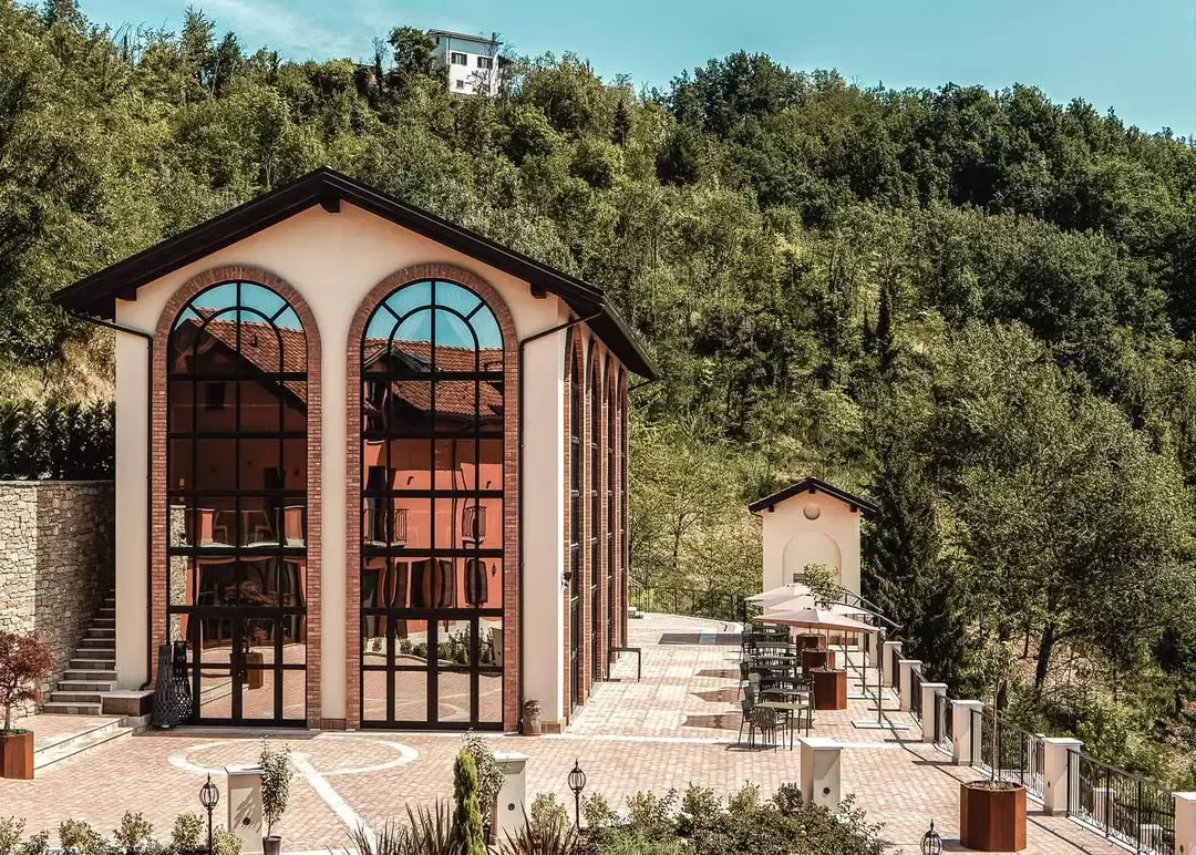 Exterior of converted wine cellar reborn as a spa and hammam with tall arched glass windows in cobbled garden