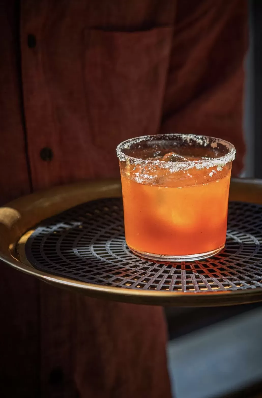 Waiter carrying Negroni cocktail served in a short glass 2 with sugar around rim on a serving tray at Gold, Notting Hill