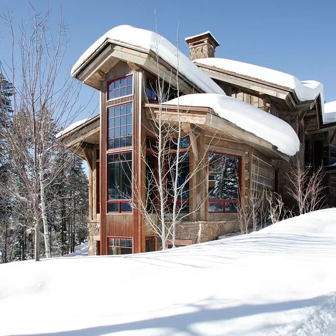 Exterior of Gold Mine Lodge sporting tall glass windows and snow on the roof in Colorado