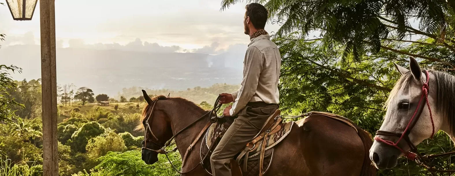 Men riding horse with a view of rainforest in Costa Rica