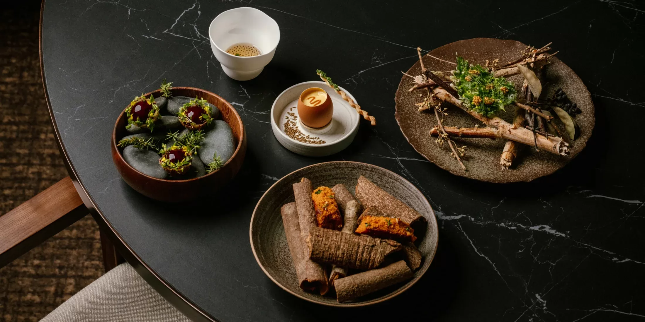 Display of beautiful, healthy dishes served on bowl plates on a black stone table at Feuille, Hong Kong