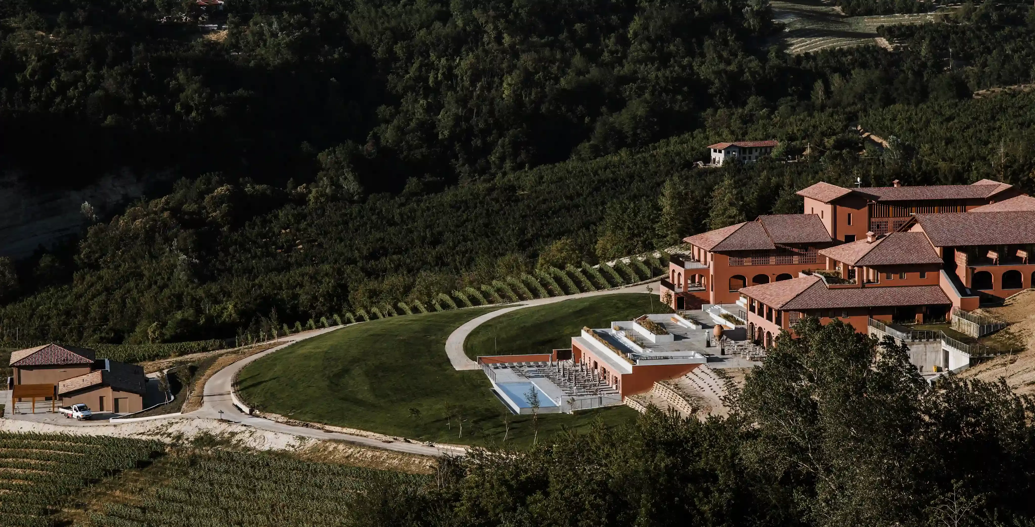 Exterior of grand red building of Casa Di Langa with outdoor pool in the Langhe Hills, overlooking 100 acres of its own vineyards, Piedmont