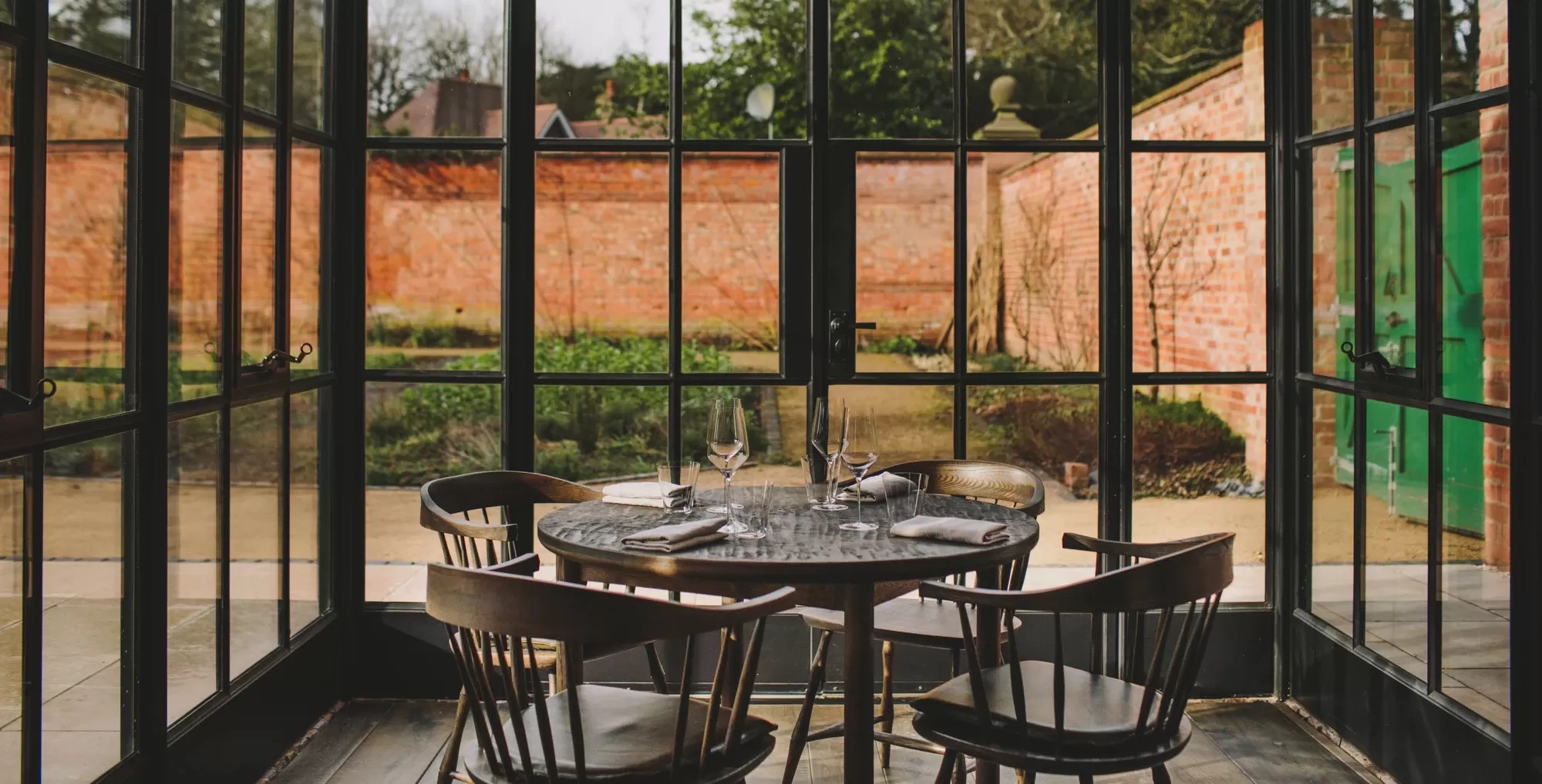 Wooden round set table and chairs with glass windows to rural view at Grace & Savour
