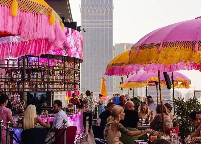 Tokyo inspired rooftop bar and brunch spot with view of Dubai city sported with yellow and pink umbrellas and people eating at Ongaku at CLAP, Dubai