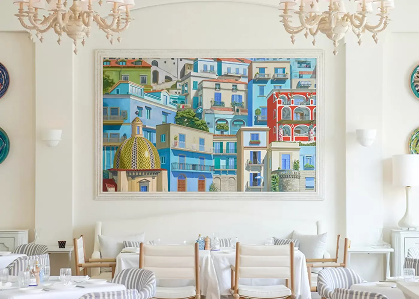 Amalfi Coast-inspired interior with white walls, chairs and tables and Amalfi painting on the wall at Alici, Bluewaters Island, Dubai