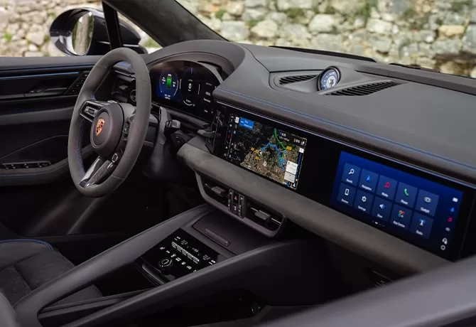 The interior of a modern car, showing the steering wheel, digital instrument cluster, and a wide touchscreen display on the dashboard with navigation and app icons visible. The design is sleek and high-tech.