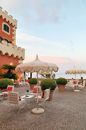 Outdoor seating areas on cobbled large balcony at Mezzatorre Hotel in Ischia, Italy