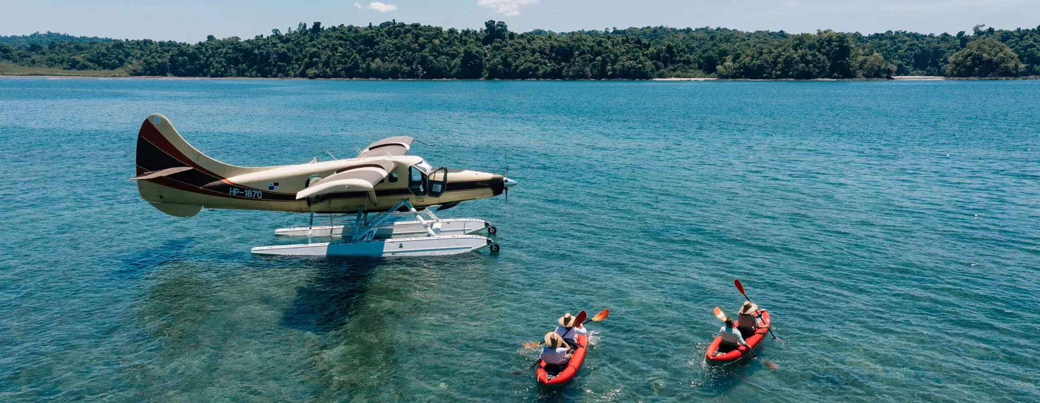Two people kayaking in the sea next to a sea plane in Isla Secas, Panama