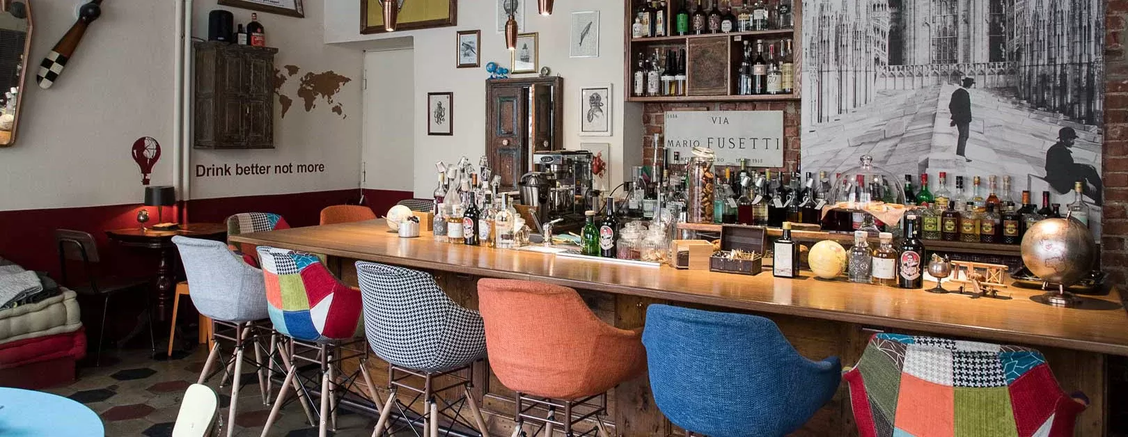 Interior of laidback retro bar with printed and coloured bar stool chairs and vintage posters at Iter, Milan