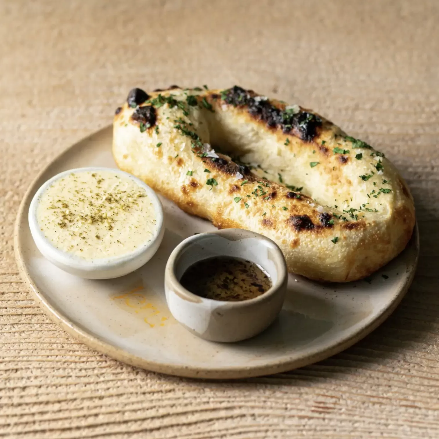 Potato bread with miso and truffle and honey dip served on a rounded plate