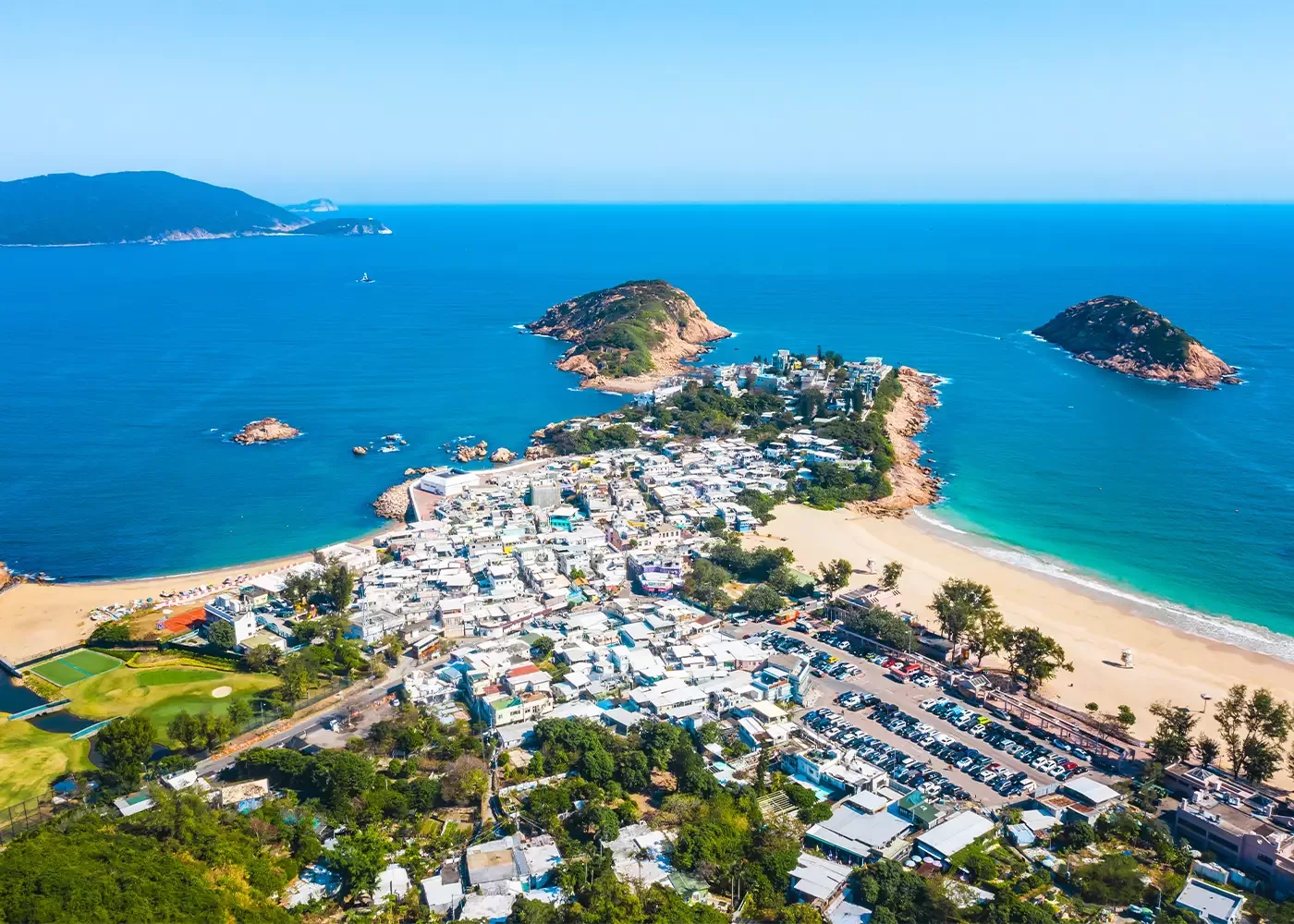 Birdseye view of blue sea and sky, islands and the beach at the end of a town in Shek O, Hong Kong Island