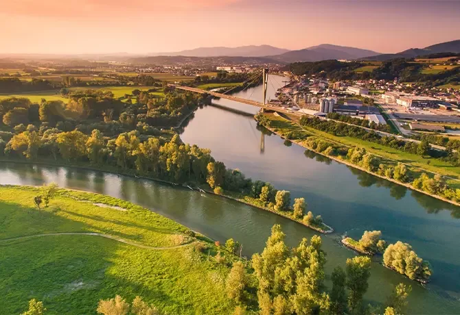 Stunning aerial view of the Isar River near Munich, showcasing lush greenery and scenic landscapes under a vibrant sunset sky.