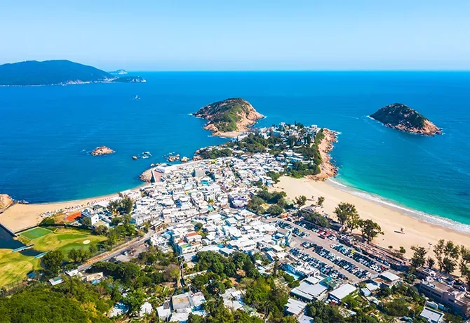 Birdseye view of blue sea and sky, islands and the beach at the end of a town in Shek O, Hong Kong Island