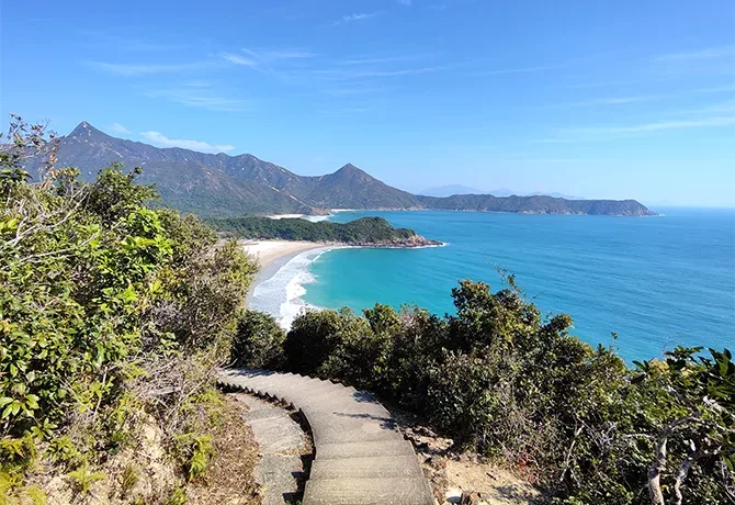 Stairway path between greenery leading down to the beach between coves and mountains in Tai Long Wan, New Territories
