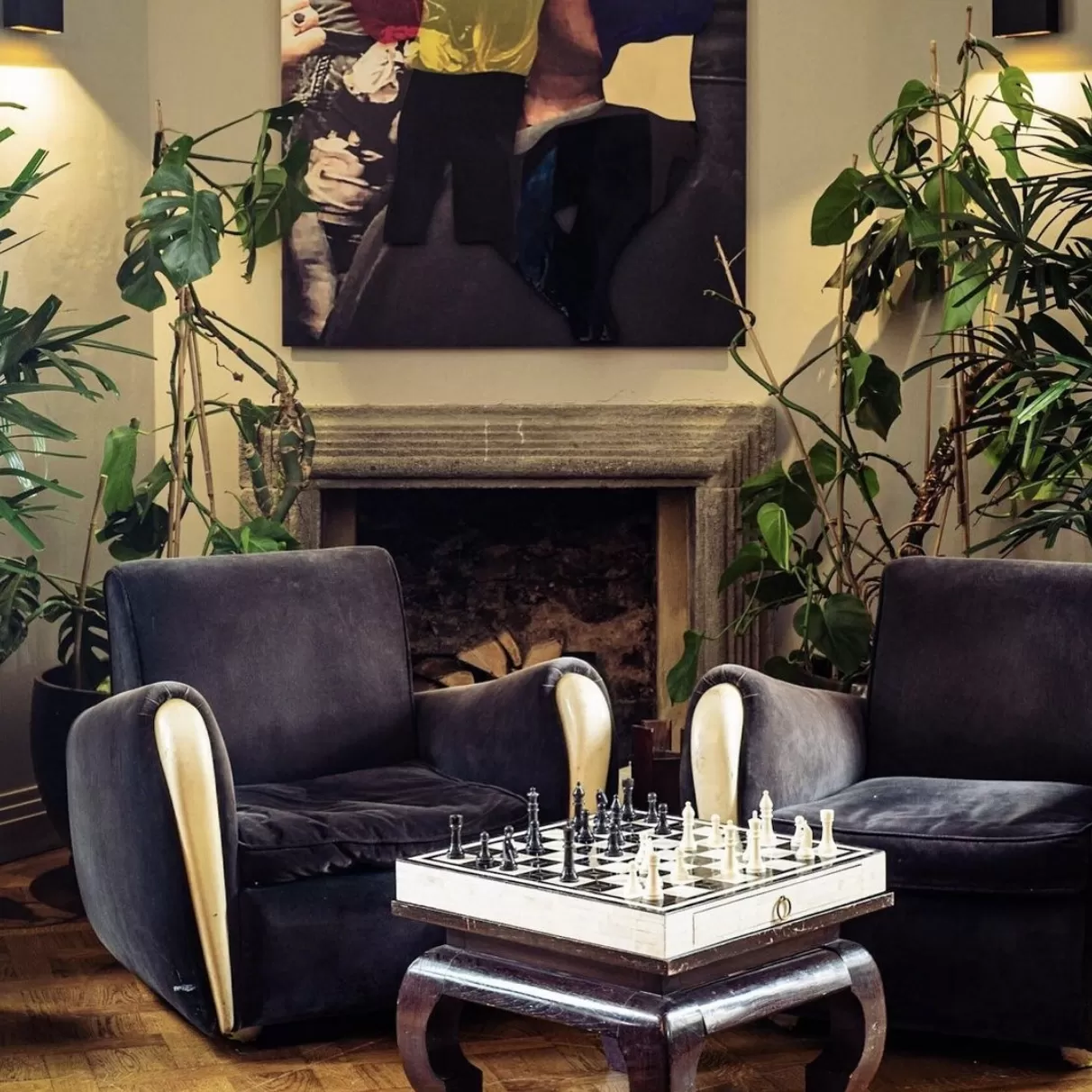 Lounge area with comfy blue velour arm chairs with a table with chess on it at Laylow, Notting Hill
