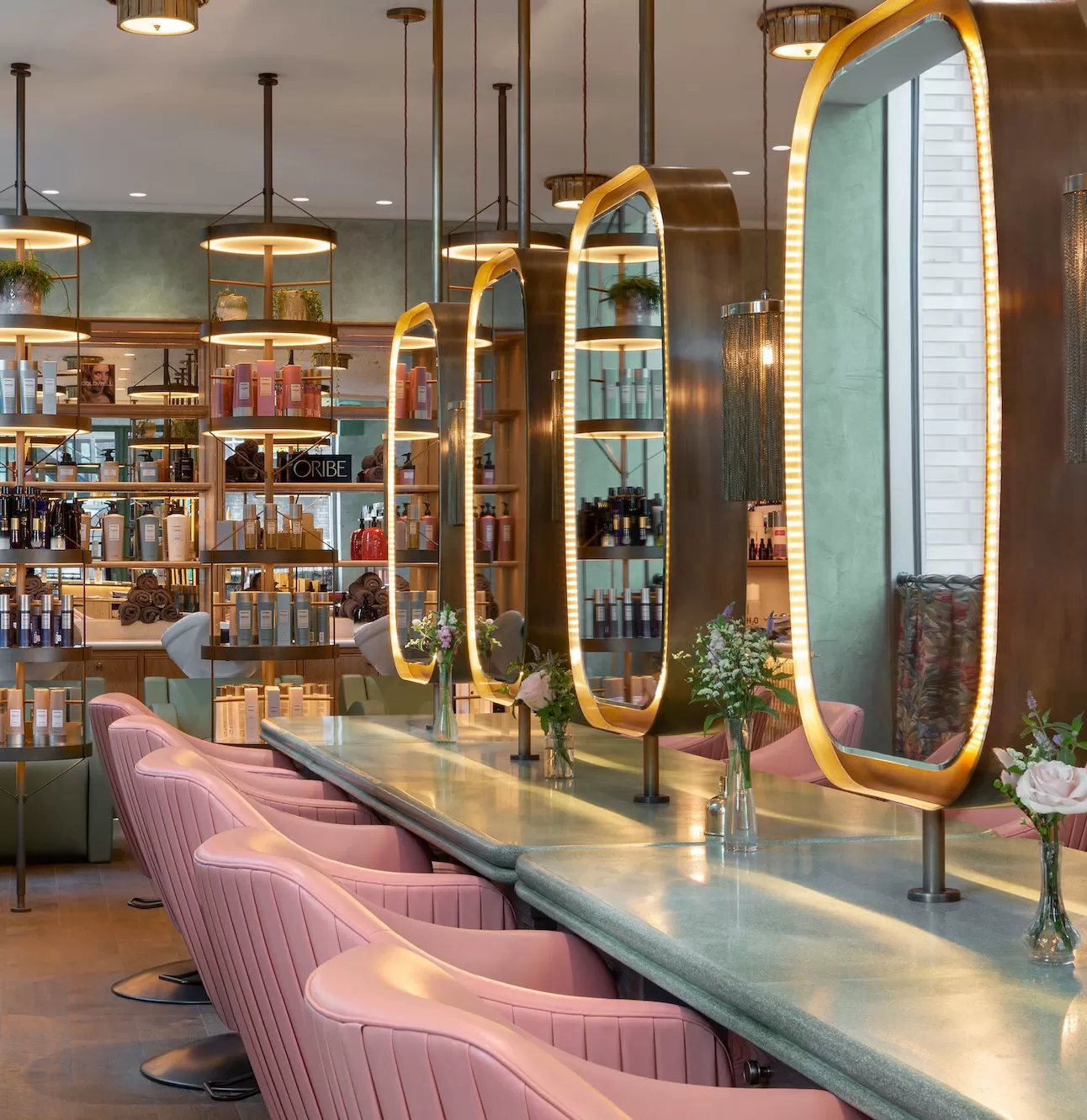Interior of hair salon Linnaen London with pink salon chairs and lit mirrors
