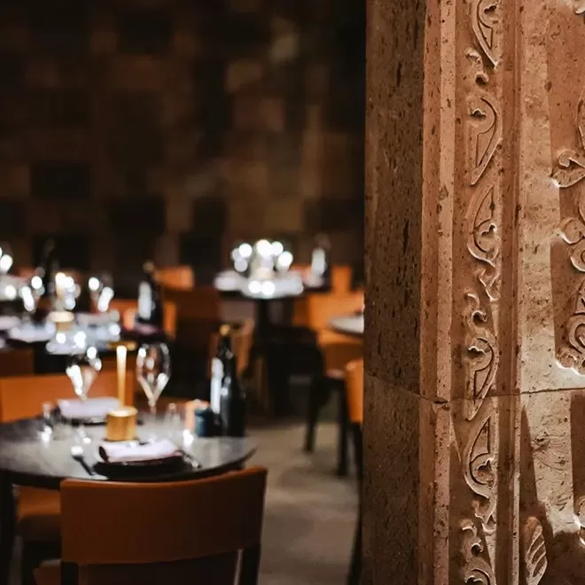 Small round 2-seater dining tables and ancient wall at Armenian restaurant Lusin, Mayfair, London