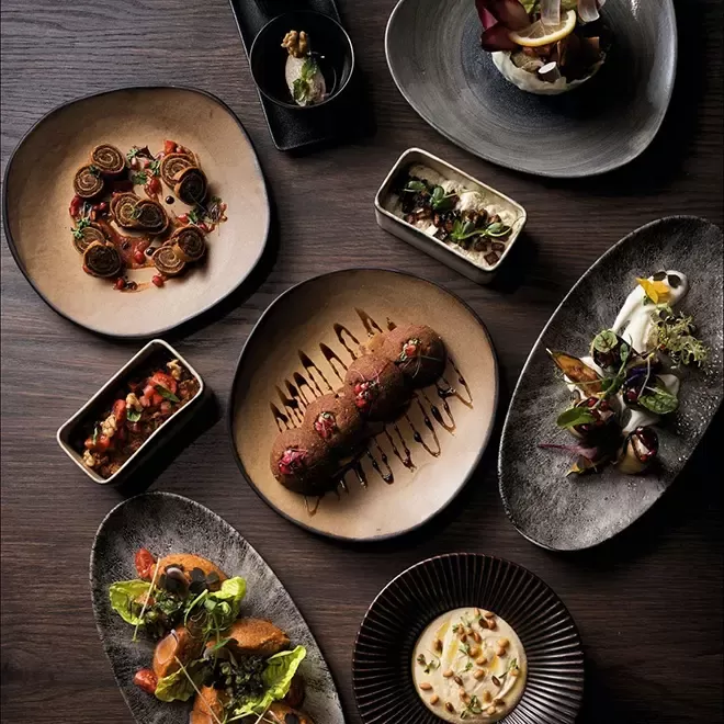 Selection of Armenian dishes served on dark round plates at Armenian restaurant Lusin, Mayfair, London
