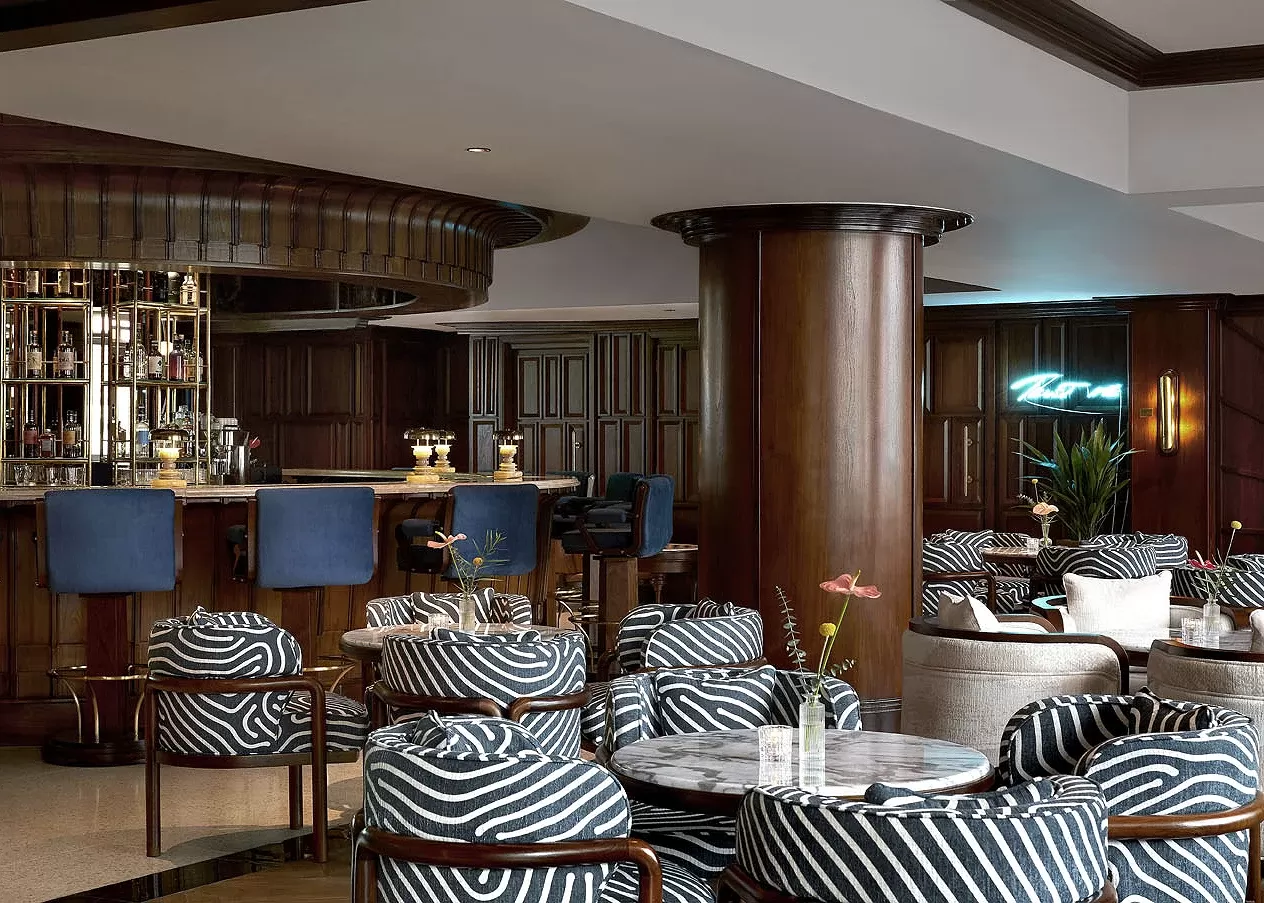 Grand bar lounge with blue stools and black and white printed chairs in seating area