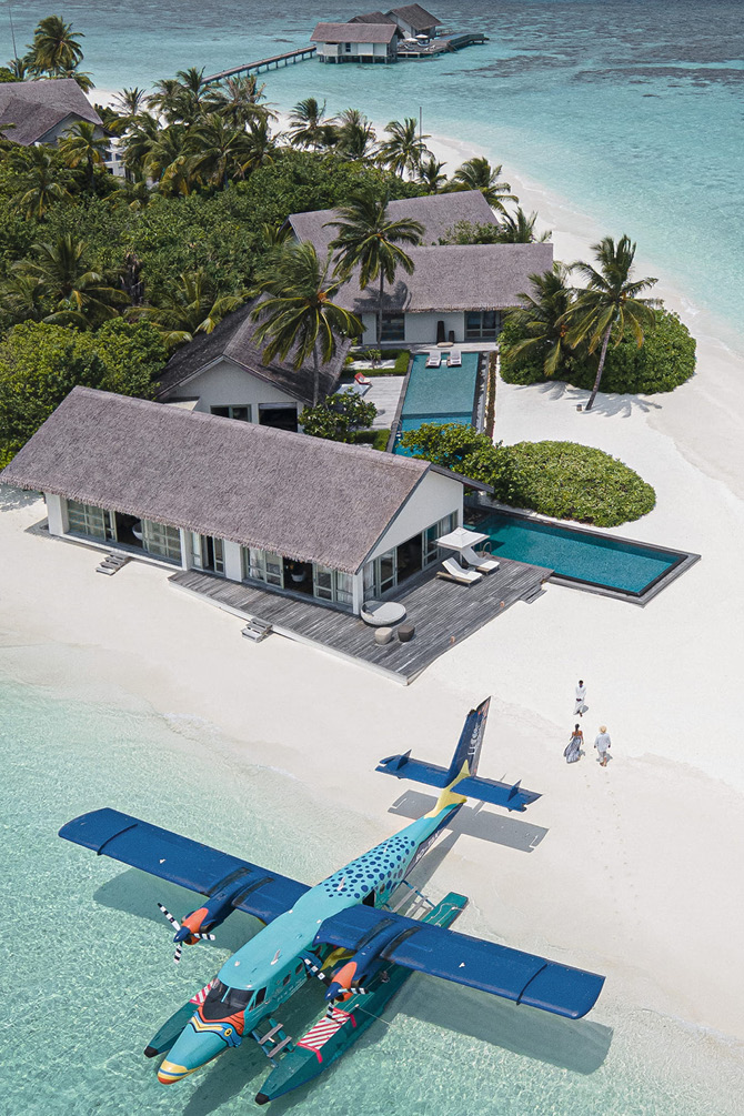 White sand beach and blue sea with a blue plane stationed on the shore of the island Voavah, Maldives
