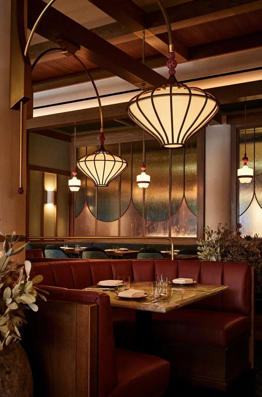 Private dining booth with red sofa interior and hanging vintage style lights at Oiji Mi, Flatiron, New York
