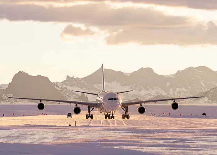 Private plane taking off on runway with pink skies and mountains behind