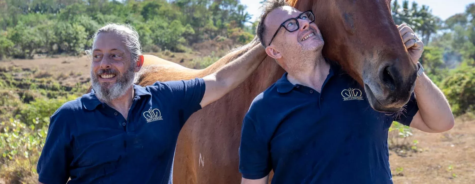 Men stroking and hugging horse in nature at Reach & Conquer Sumba, Indonesia