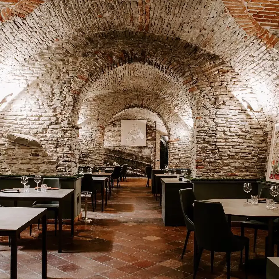 Interior of arched cellar type minimalistic restaurant with stone arched ceilings at Michel Star restaurant in Relais San Maurizio